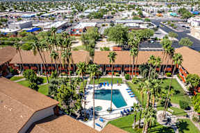 A pool surrounded by palm trees and a building.