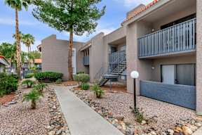 A concrete pathway leads to a building with a balcony.