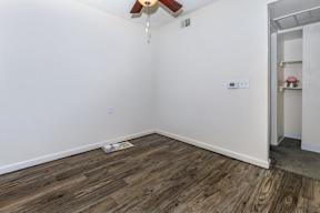 A room with a ceiling fan and wooden flooring.