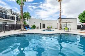 A swimming pool surrounded by a black fence and palm trees.at Icon Apartments, Arizona