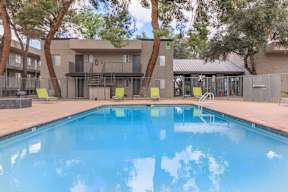 A swimming pool in front of a building surrounded by trees.