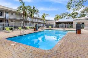 A swimming pool surrounded by a brick patio and palm trees.