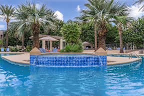 A pool surrounded by palm trees and a gazebo.