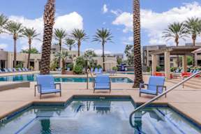 A pool surrounded by palm trees and lounge chairs.