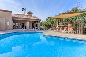 A swimming pool with a sun lounger and a building in the background.