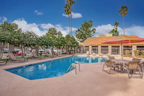 A pool with chairs and a building in the background.