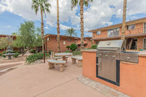 A patio with a table and chairs and a grill.