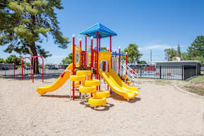 A playground with a yellow slide and a blue canopy.