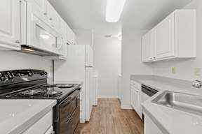 A white kitchen with a stove, oven, and sink.