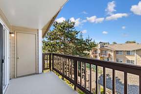A balcony with a view of apartment buildings and trees.