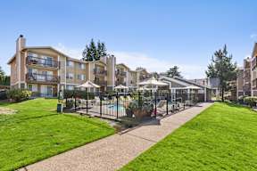 A sunny day at a residential complex with a pool and green lawns.