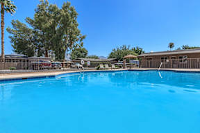 A swimming pool surrounded by a fence and trees.