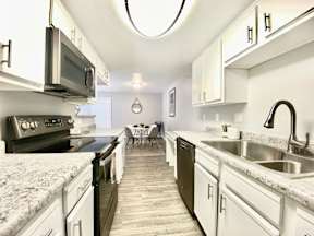 A kitchen with black appliances and white cabinets.at Icon on Midvale, Tucson, AZ