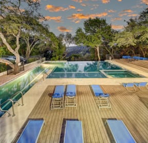 the swimming pool at the resort has a wood deck with blue chairs