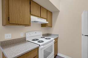 A kitchen with a white stove top oven and a white refrigerator.