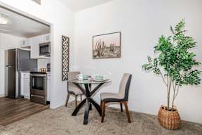 A dining area with a table and chairs and a potted plant.