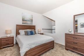 A bedroom with a bed, nightstands, and a mirror.