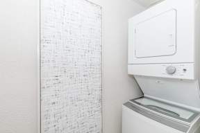 A white dryer is next to a white wall with a list of items on it.