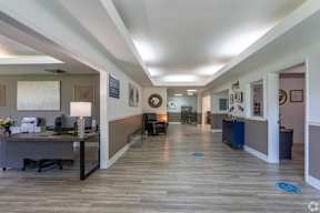 A hallway with a desk and chairs on the left and a doorway on the right.