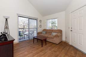 A living room with a tan couch and a wooden floor.