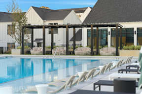 A pool with chairs and a building in the background.