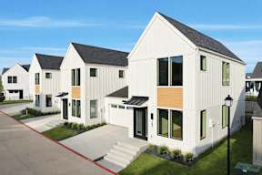 A row of modern houses with white exteriors and wooden accents.
