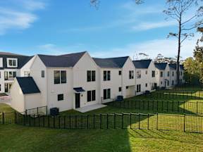 A row of white houses with black roofs and fences.
