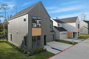 A modern house with a grey exterior and a red driveway.