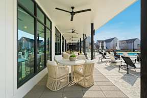 A patio with a table and chairs and a ceiling fan.