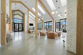 A spacious lobby with a white floor and ceiling, wooden beams, and a mix of seating options.