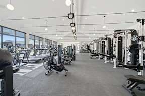 A spacious gym with various exercise equipment and a large window.