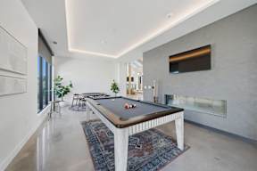 A pool table is in the middle of a room with a television on the wall.