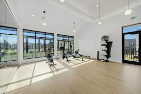 A gym with exercise equipment and a view of the outside.