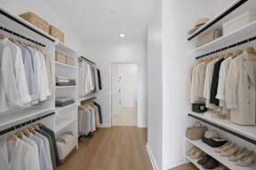 A walk in closet with clothes and shoes.