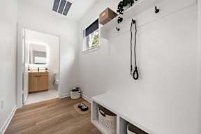 A white room with a wooden floor and a white bench.