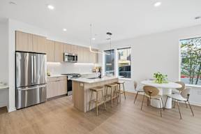 A modern kitchen with a refrigerator, stove, and dining table.