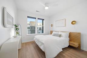 A bedroom with a bed, a window, and a ceiling fan.