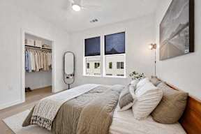 A bedroom with a large bed and a window with a view of a cityscape.