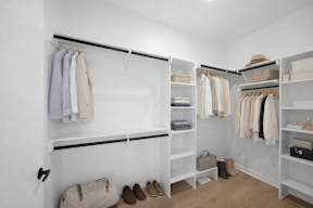 A white closet with clothes and shoes.