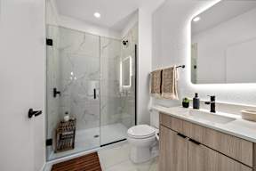 A modern bathroom with a glass shower and a white toilet.
