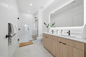 A bathroom with a white tiled shower and a white counter top.