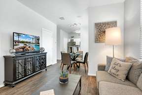 A living room with a grey couch, a wooden table, and a painting on the wall.