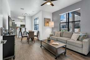 A living room with a grey couch, a coffee table, and a ceiling fan.