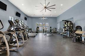 A gym with a variety of equipment including treadmills, stationary bikes, and weight machines.