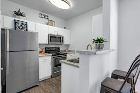 A kitchen with a refrigerator, stove, and microwave.