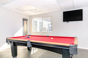 A pool table in a room with a television mounted on the wall.