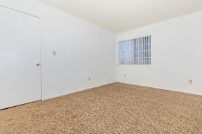 A room with a carpeted floor and a window with bars.