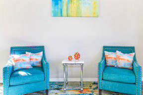 Two blue chairs with pillows and a small table between them.