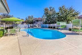 A blue swimming pool surrounded by a green fence and trees.