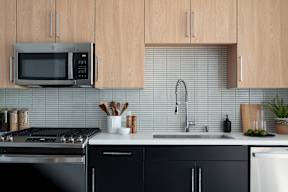 A kitchen with black cabinets and a stainless steel oven.